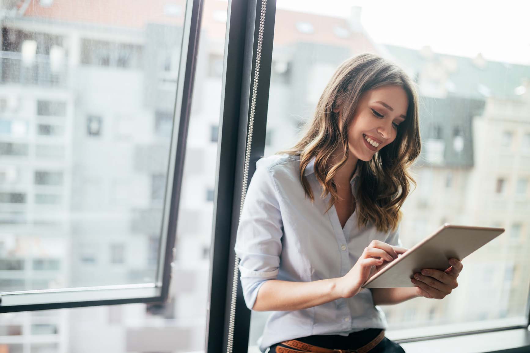 image of woman looking at ipad by window smiling